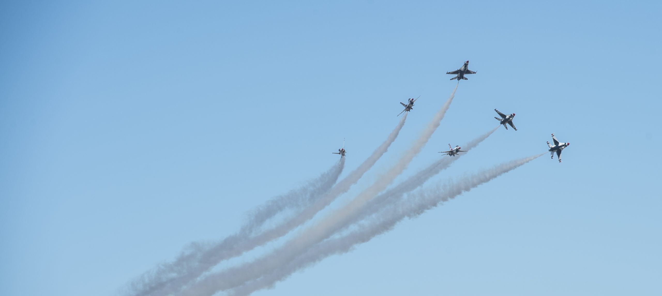 Six jet planes flying through the air with smoke trailing behind them