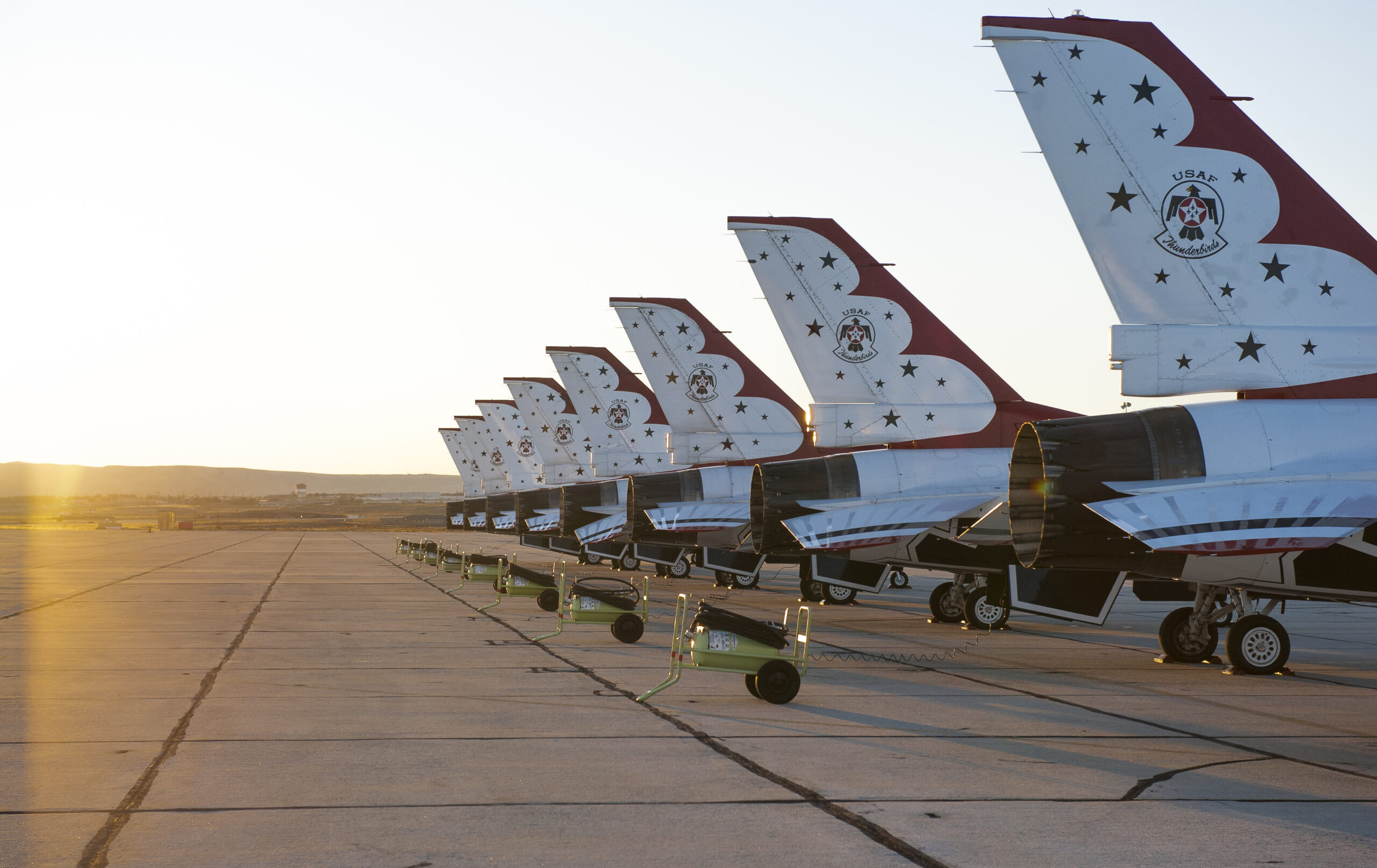 8 jets on a landing strip all parked in a line